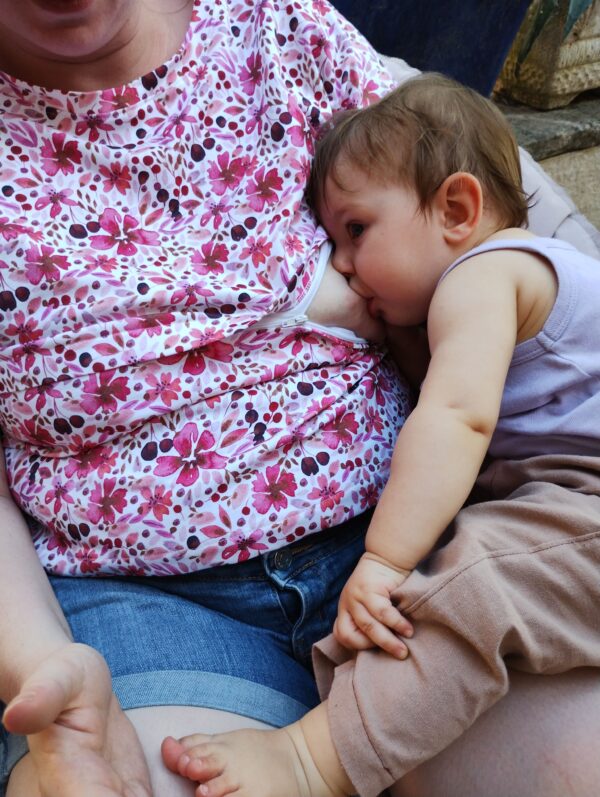 Maman et bébé en train de téter. Maman porte un t-shirt d'allaitement motif fleurs roses